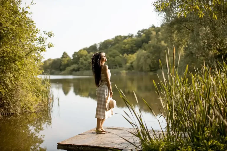A young woman stands on a dock and enjoys the sun.