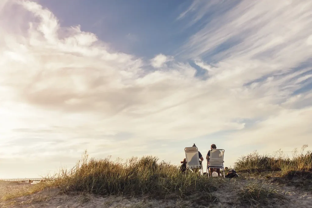 rear view of people sitting on a grassy beach in florida