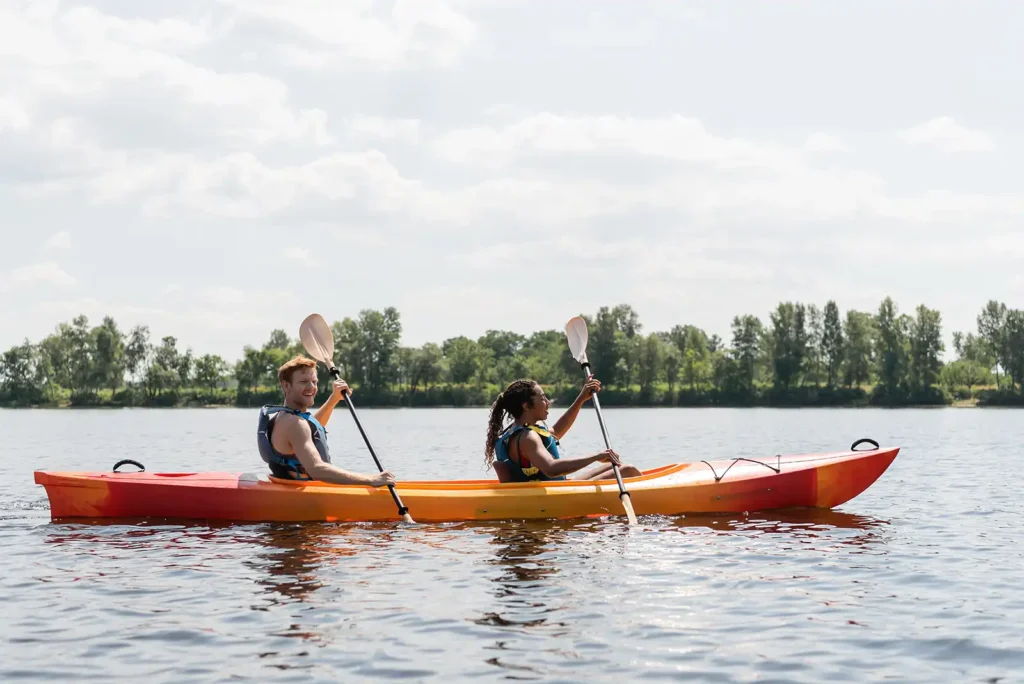 side view of smiling redhead man and brunette woman in kayak